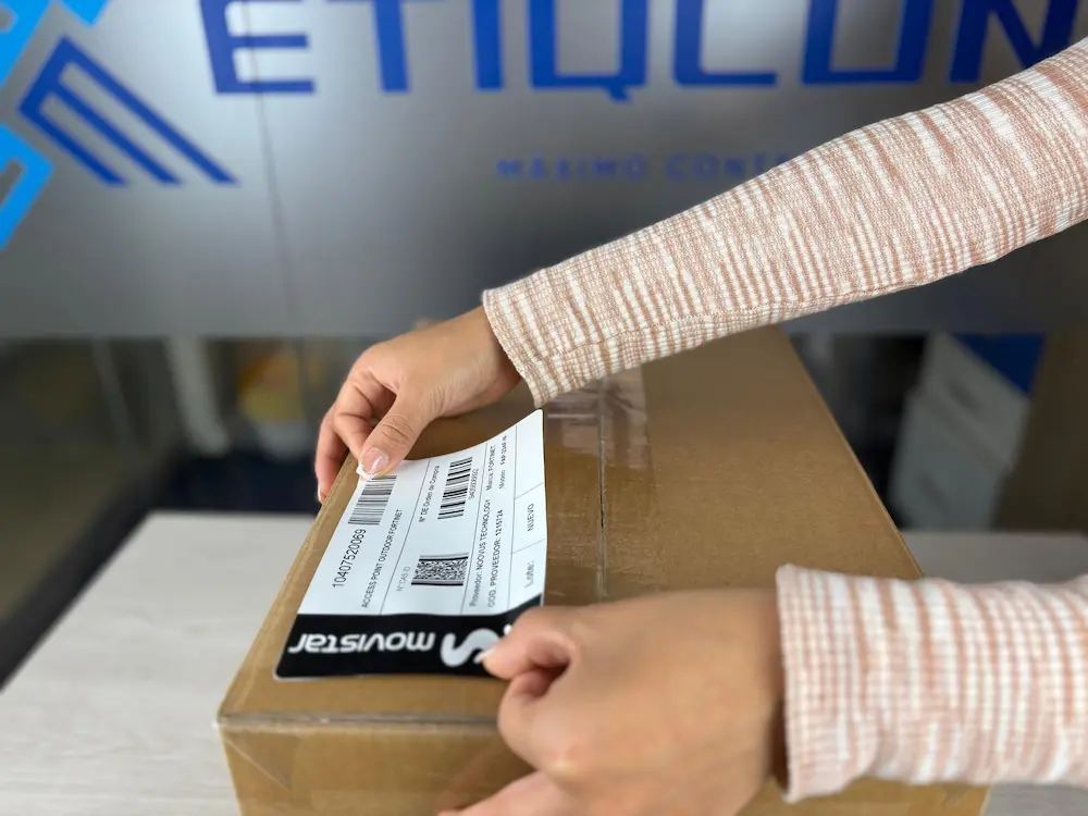 una persona pegando etiqueta ashesiva - Qué son las soluciones de etiquetado