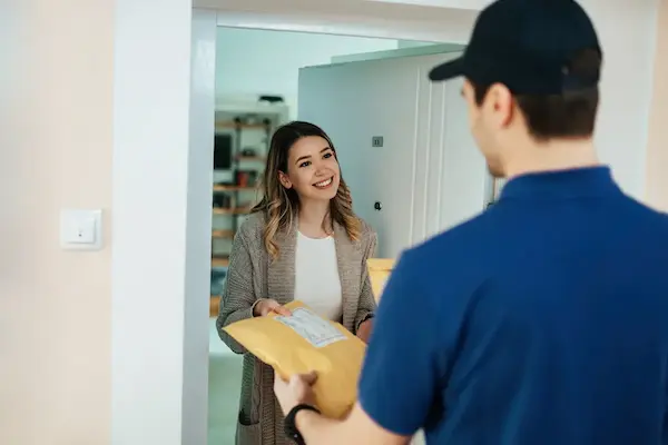 mujer recibiendo pedido de repartidor en la puerta de su casa