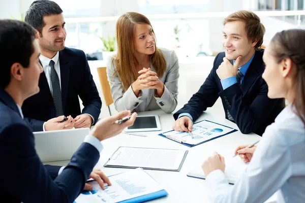 conversación entre miembros del equipo que están sentados en una mesa de trabajo