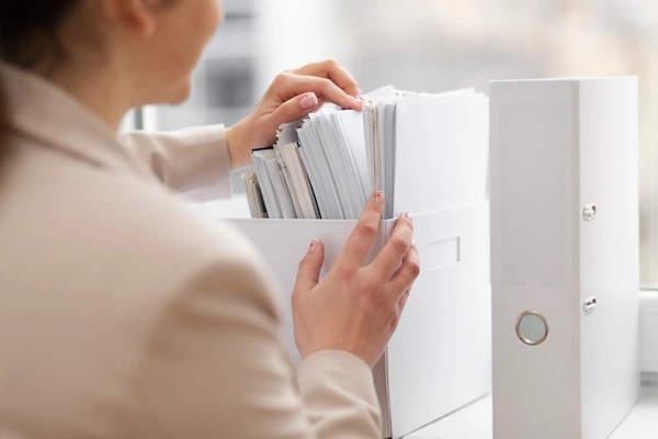 mujer empresaria revisando archiveros para generar un sistema de gestión documental
