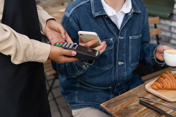 persona pagando a mesera mediante la tecnología NFC