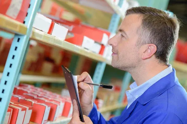 hombre realizando el conteo de inventario en almacén lleno de cajas