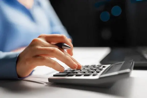 primer plano de la mujer de negocios con calculadora contando y llenando formulario del Impuesto a la Renta empresarial