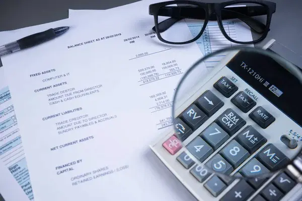 Documentos financieros, calculadora y lentes sobre una mesa, ideales para ilustrar la gestión contable de un negocio acogido al NRUS