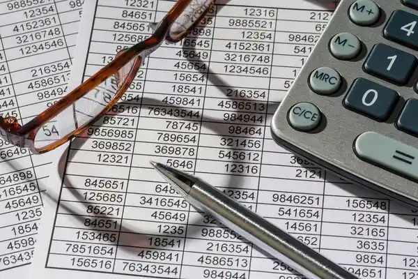 Manos usando una calculadora sobre declaraciones fiscales mientras se preparan los datos para los libros electrónicos SUNAT