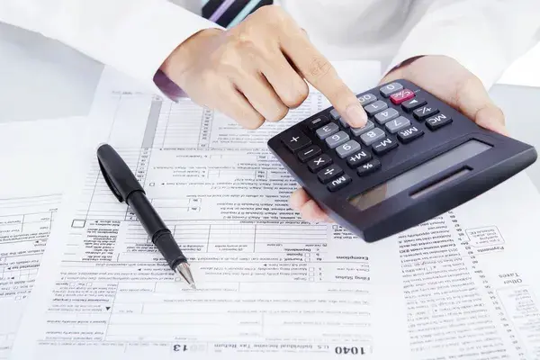 Profesionales revisando formularios tributarios con calculadora y lapicero para gestionar los libros electrónicos SUNAT.